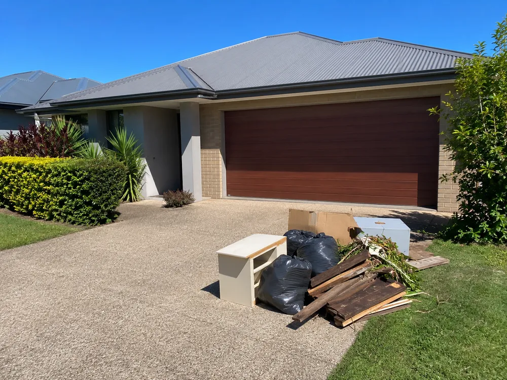 Driveway piled with household rubbish, furniture and green waste before a BINZA clean-up